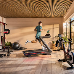Model running on adidas T-700 Treadmill surrounded by home gym equipment