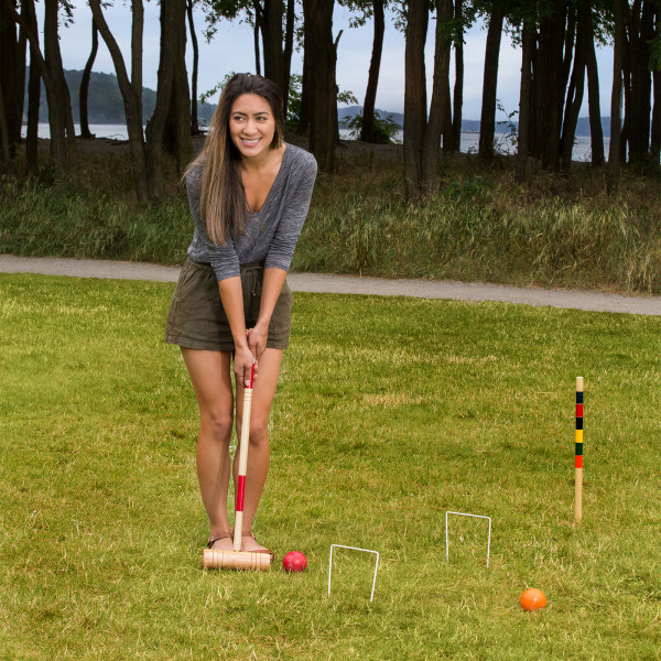 A person preparing to hit a croquet ball with a mallet.
