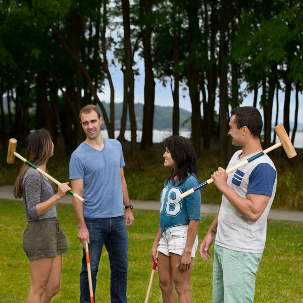 Group of people chatting while holding croquet mallets.