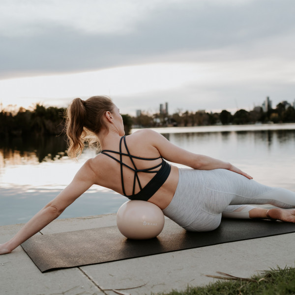 Lifestyle image of a model performing a side hold exercise with the BAHE Flowball 
