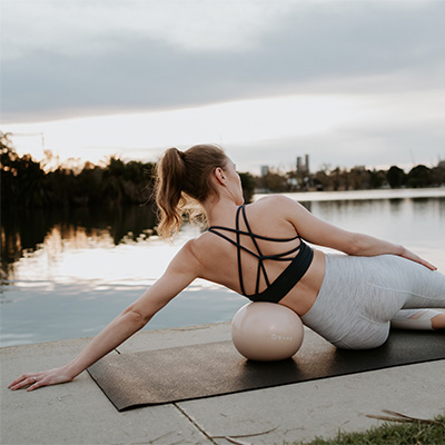 Lifestyle image of a model using the BAHE Flowball during a side exercise.