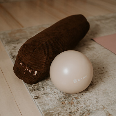 A lifestyle image of the BAHE Yoga Bolster and the BAHE Flowball