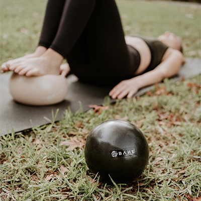 Image of a model using one of the Flowball Duet balls for a balancing exercise, the second ball is in the focus of the shot.