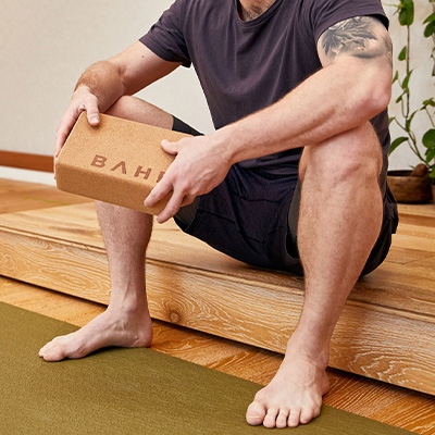 Lifestyle image of the BAHE Cork Yoga Block in the hands of a sitting model