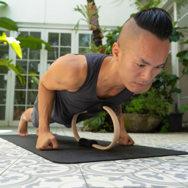 A lifestyle image of the BAHE Pilates Ring being used by a model during a plank. The ring is being used against the chest.