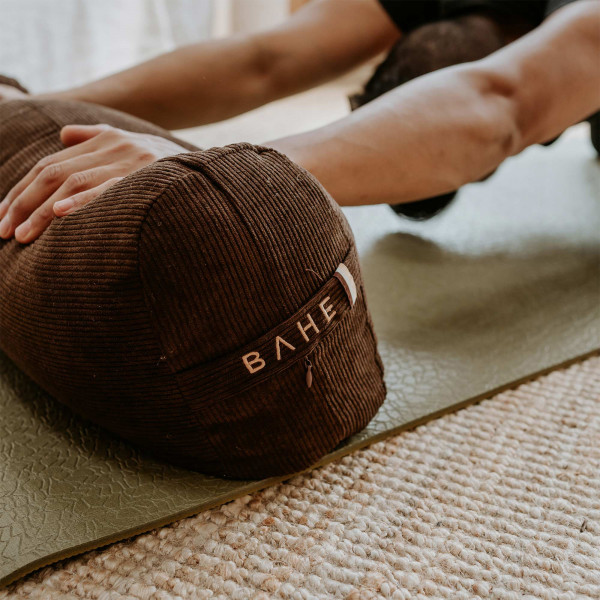 Lifestyle image of the BAHE Yoga Bolster being used during a stretch