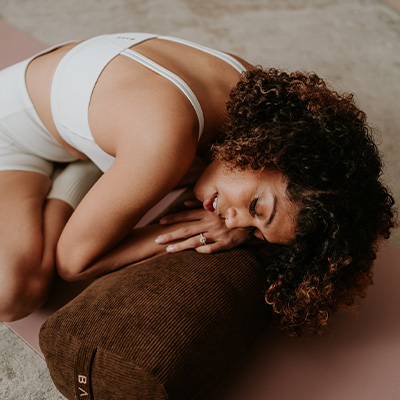 Lifestyle image of a model lying down on the BAHE Yoga Bolster