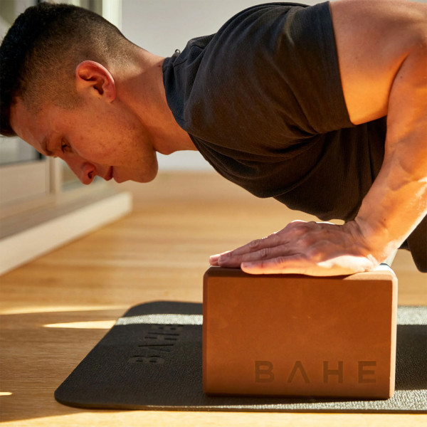 A lifestyle image of a model using the BAHE Yoga Block during a press-style pose.