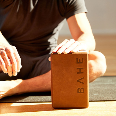 Photograph of a model sitting by the BAHE Yoga Block