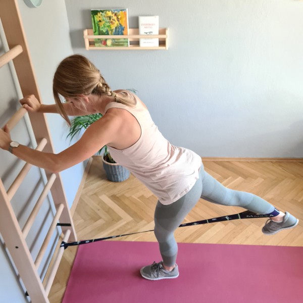 User performing resistance band leg exercise using BenchK 100 Wall Bars
