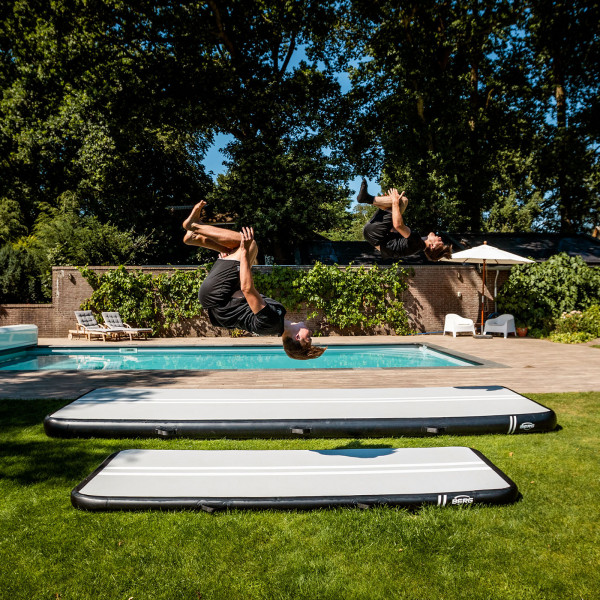 Athletes performing backflips on BERG AirTrack Home near a pool.