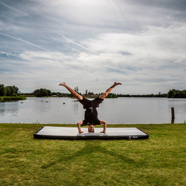 Athlete balancing in a headstand on BERG AirTrack Home by the lake.