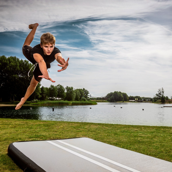 Athlete diving forward onto BERG AirTrack Home by a lake