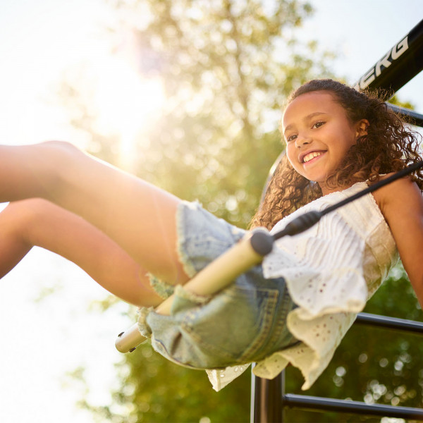 Girl smiling while swinging on the BERG PlayBase Trapeze