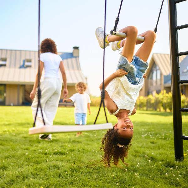 Child hanging upside down on the BERG PlayBase Trapeze