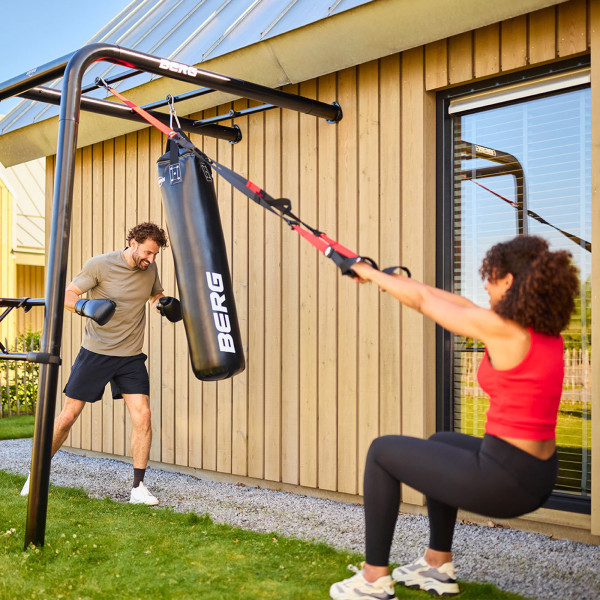 Two people using BERG PlayBase Boxing Bag and training strap