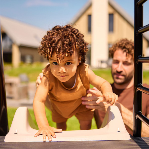 Toddler climbing up the BERG PlayBase slide with adult support
