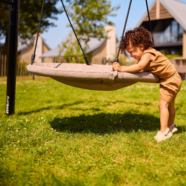Toddler pushing a round swing on the BERG PlayBase
