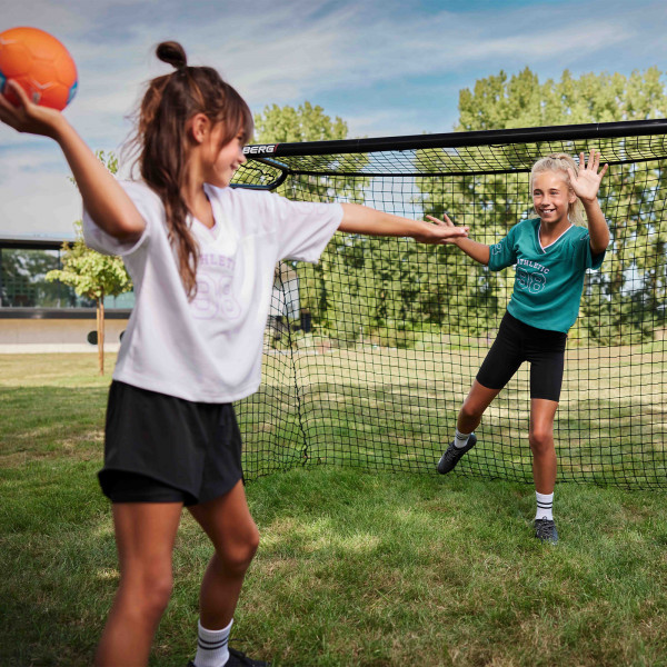 Two players playing handball in front of the BERG SportsGoal.
