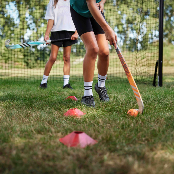 Two players practicing hockey with cones in front of the BERG SportsGoal.
