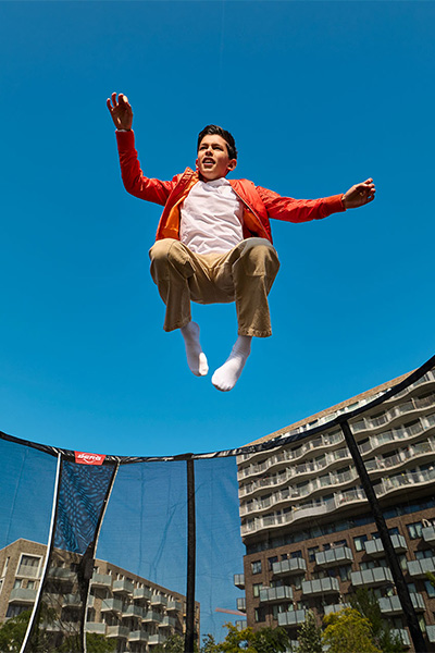 Low angle shot of the model jumping on the BERG Champion Regular Trampoline with Safety Net Deluxe