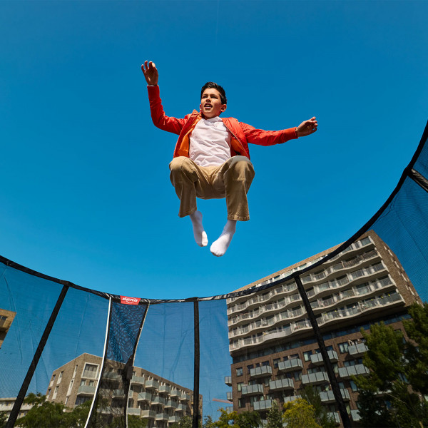 Low angle shot of the model jumping on the BERG Champion Regular Trampoline with Safety Net Deluxe