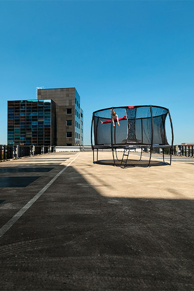 Wide shot of the model jumping on the BERG Champion Regular Trampoline with Safety Net Deluxe