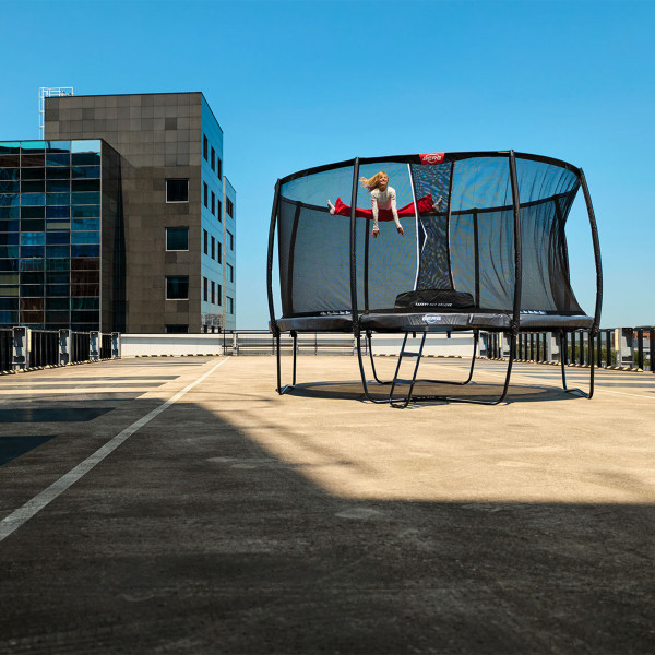 Wide shot of the model jumping on the BERG Champion Regular Trampoline with Safety Net Deluxe