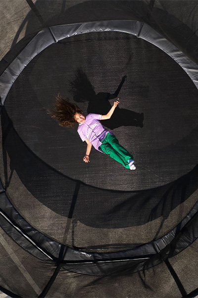 Top view shot of the model lying on the BERG Champion Regular Trampoline with Safety Net Deluxe