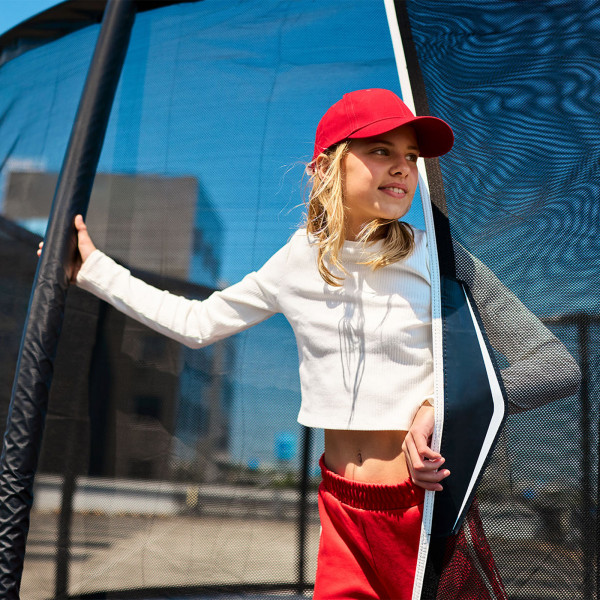 Close-up of the model standing at the entrance of the BERG Champion Regular Trampoline with Safety Net Deluxe