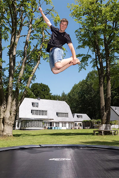 Action shot of the model performing a jump on the BERG Sports Champion InGround Trampoline