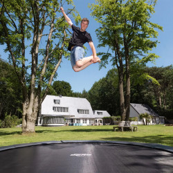 Action shot of the model performing a jump on the BERG Sports Champion InGround Trampoline