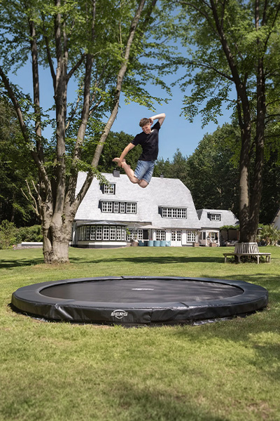 Wide shot of the model jumping on the BERG Sports Champion InGround Trampoline