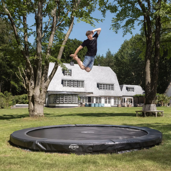 Wide shot of the model jumping on the BERG Sports Champion InGround Trampoline