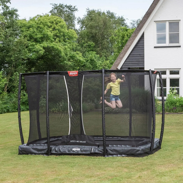 Wide shot of the model jumping on the BERG Ultim Champion InGround Trampoline with Safety Net Deluxe