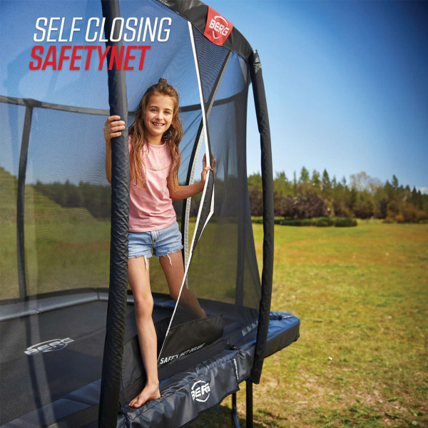 Model standing at the self-closing safety net entrance of a BERG Champion trampoline