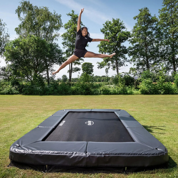 Action shot of the model performing a high jump on the BERG Sports Ultim Champion InGround Trampoline