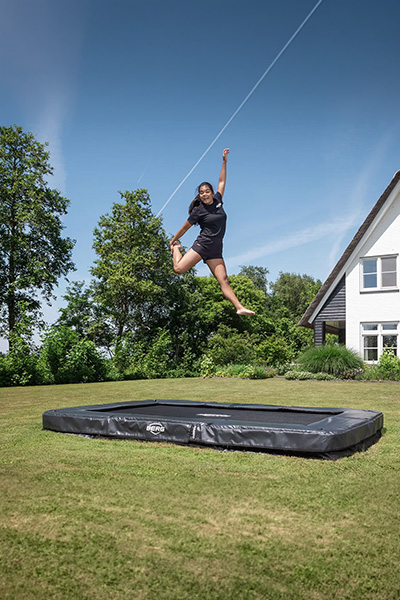 Wide shot of the model jumping on the BERG Sports Ultim Champion InGround Trampoline