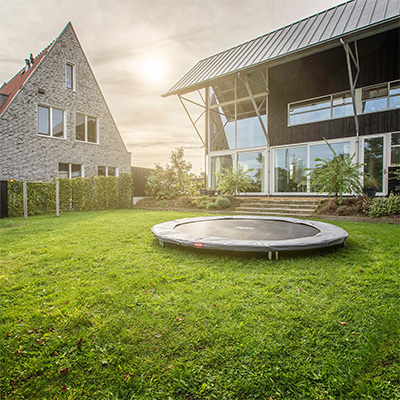 BERG Sports Favorit Inground Trampoline assembled in a spacious back garden beside a house
