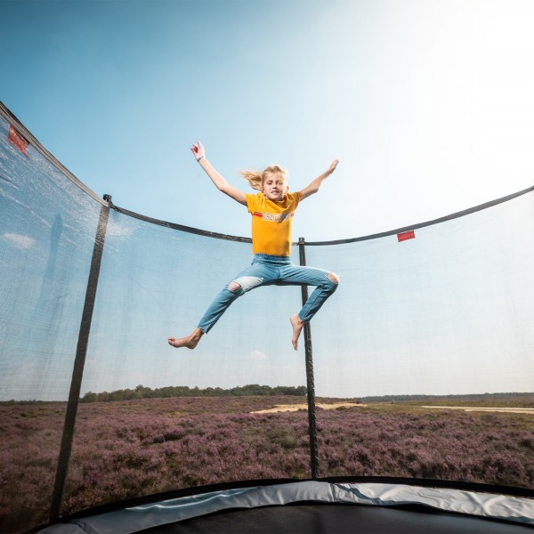 A child jumping on the BERG Favorit Regular Trampoline With Safety Net Comfort.
