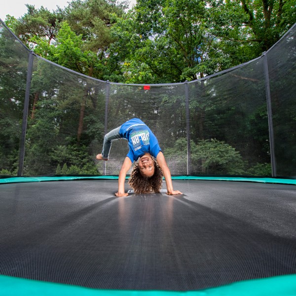 A child having fun on the BERG Favorit Regular Trampoline With Safety Net Comfort.
