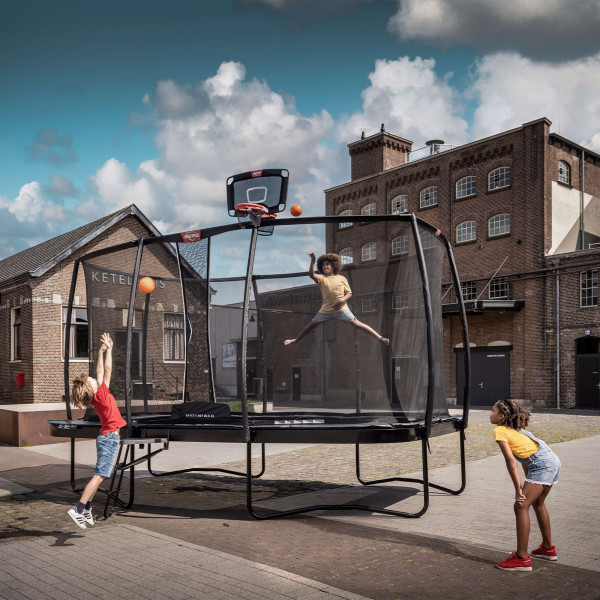 Three children playing basketball on a trampoline with the BERG TwinHoop Basketball Hoop.
