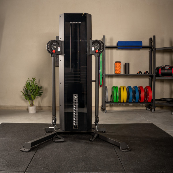 Front view of the BodyCraft EFT Functional Trainer with accessories in the background. 