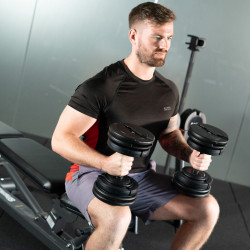 User holding two BodyMax 34 kg Selectabell Adjustable Dumbbells seated
