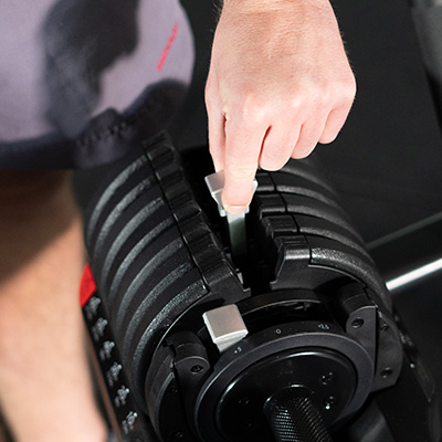 Close up of user adjusting the BodyMax 25 kg Selectabell Adjustable Dumbbell plates