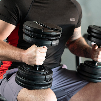 User holding two BodyMax 25 kg Selectabell Adjustable Dumbbells seated