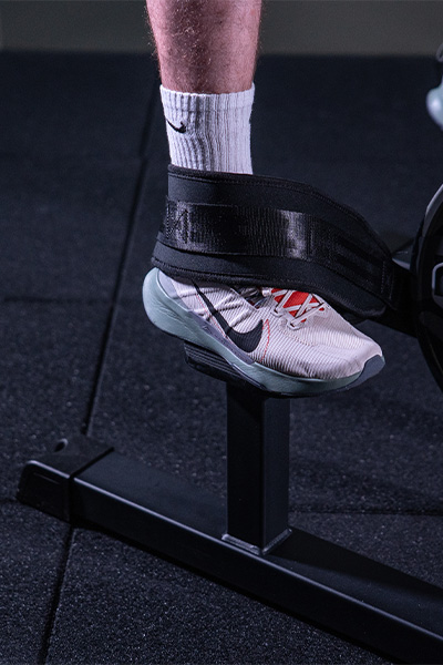 close-up of user foot strapped on gym machine with gym flooring underneath