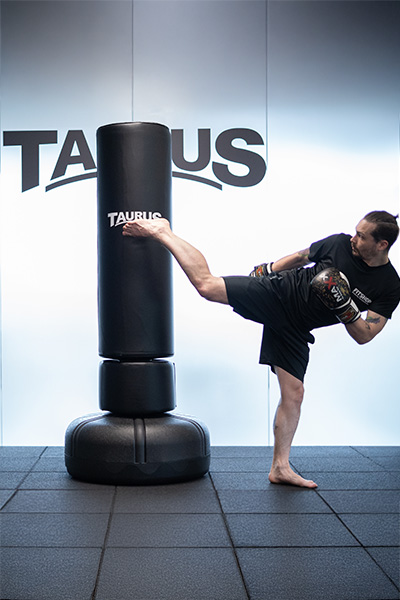 user kicking a free-standing punch bag on gym flooring