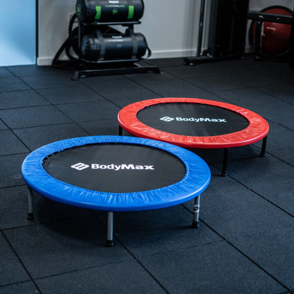 Angled view of the BodyMax Mini Fitness Trampolines in blue and red placed on gym floor