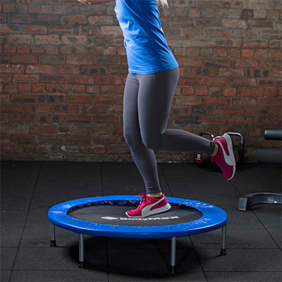 Side view of a user performing single-leg balance on the BodyMax Mini Fitness Trampoline in blue 